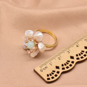Primo piano dettagliato dell'anello fiore perla barocca regolabile con perla verde.