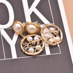 Close-up detail of geometric wire-wrapped pearl earrings with glossy pearls and elegant gold tone.