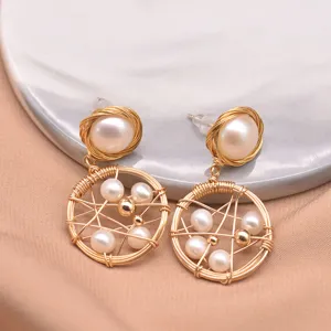 Closeup of handmade gold wire wrapped freshwater pearl geometric drop earrings detail.