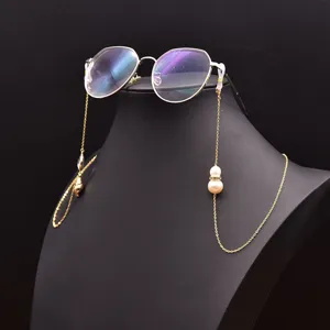 Detailaufnahme einer eleganten goldenen Brillen- und Maskenkette mit schicken Perlen.