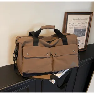 Detailaufnahme der braunen Reisetasche mit Doppelvordertaschen und stabilen schwarzen Gurten.
