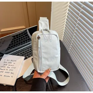 Detailed view of light blue checkered crossbody chest bag with zipper pockets and adjustable strap.