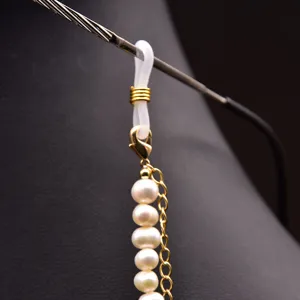 Détail de chaîne de lunettes en perles d'eau douce avec maillons dorés et boucles silicone.
