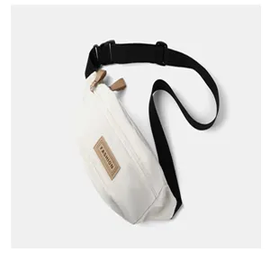 Weiße Canvas-Brusttasche mit schwarzem Gurt und modischem Aufnäher für urbane Streetwear.