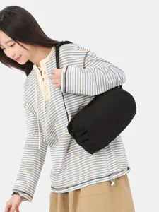Minimalist black nylon crossbody bag worn by a model, casual lightweight everyday shoulder bag.