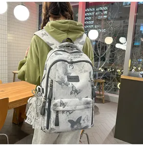Detailansicht des großen Schülerrucksacks mit grauem Schmetterlingsdruck und Anhängern.