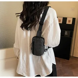 Detailed shot of a black and white plaid sling chest bag worn on back, perfect for travel.