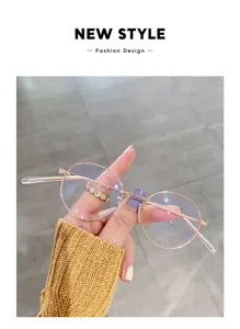 Nahaufnahme einer stilvollen runden Metallbrille mit Blaulichtfilter, elegant in Hand gehalten.