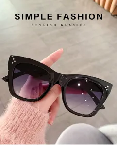 Primer plano de gafas de sol cat-eye negras de moda con lentes degradadas y detalles.