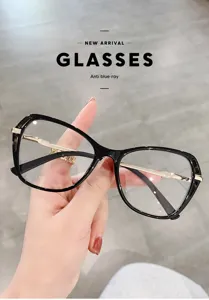 Gros plan de montures de lunettes pour femmes en acétate noir et branches en métal doré.