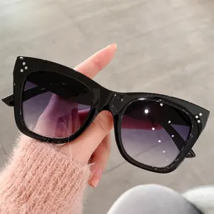 Gafas de sol de ojo de gato de moda para mujer con lentes degradadas y montura negra.