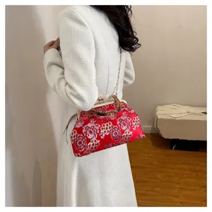 Detailaufnahme einer roten blumenbestickten Abendtasche mit Bambusgriff und Kette.