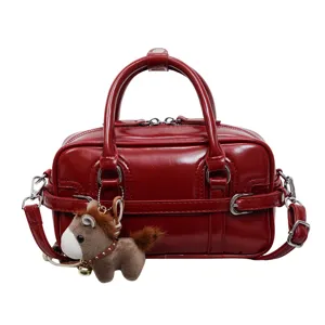 Close-up of the glossy red PU square handbag with metal hardware and cute horse charm detail.