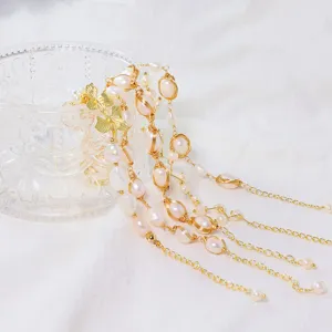 Nahaufnahme eines handgefertigten Perlenarmbands mit Golddraht und Blumenanhängern.