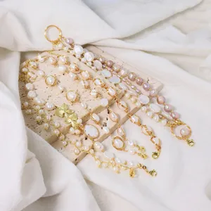 Detailansicht von vergoldeten Perlenarmbändern mit Barockperlen und Schmetterlingsanhängern.
