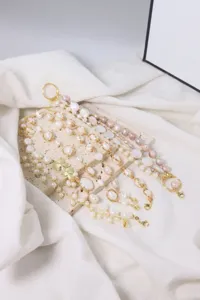 Nahaufnahme handgefertigter Barockperlen-Armbänder mit goldenem Draht und Schmetterlingen.