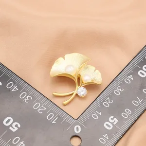 Elegant matte gold ginkgo leaf brooch with freshwater pearls and sparkling zircon charm.