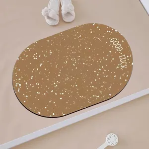 Detailed view of the oval brown floor mat with white speckles and Good Luck text in bathroom setup.