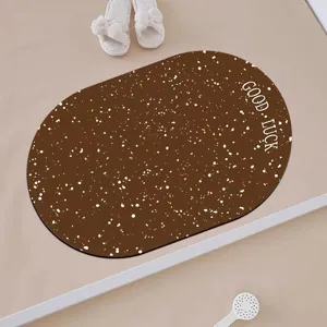 Close up view of brown oval absorbent floor mat with white speckle and cute letter print.