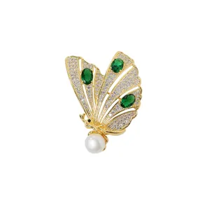 Elegant gold plated butterfly brooch featuring sparkling cubic zirconia, green gems, pearl.