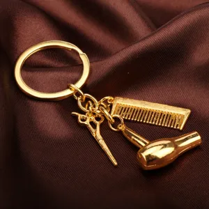 Primer plano detalle de un bonito llavero de peluquería dorado con tijeras y peine pequeños.