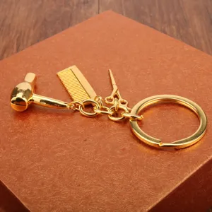 Llavero de peluquería de metal dorado con dijes de secador peine y tijeras bonito diseño.