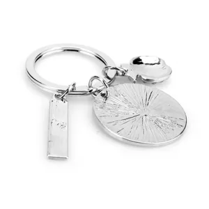 Detaillierter Metall-Schlüsselanhänger mit Lineal, Sonnenstrahl-Scheibe und Apfel.