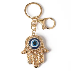 Detailed view of gold-plated Hamsa Hand keychain featuring blue evil eye and crystal accents