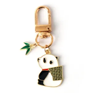 Close-up view of a cute panda enamel keychain with a green bamboo leaf charm accessory