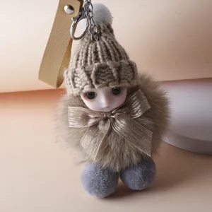 Detailed view of a cute doll plush keychain featuring a knitted hat and golden bow