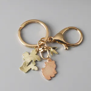 Detail view of gold-tone keychain with panda and fan charms on gray background.