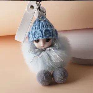 Close-up detail of cute plush doll keychain with blue knitted hat and silver bow