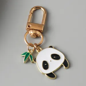 Detailed view of a cute panda enamel charm with bamboo leaf on a gold keychain clasp
