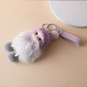 Detail shot of a cute plush doll keychain with purple knit hat and grey fur ball.