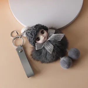 Close-up detail of cute grey faux fur doll keychain featuring a silver bow and leather strap
