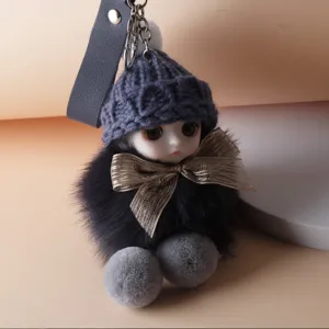 Close-up detail of a cute plush doll keychain with a knitted hat and golden bow charm