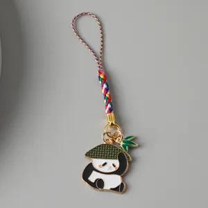 Detailed macro view of a cute panda keychain with colorful woven strap and green hat