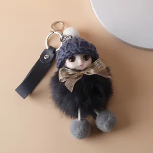 Detailed view of a cute doll keychain with fluffy fur pom-pom and purple knitted hat