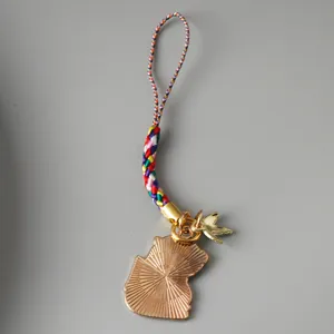 Detail of a Chinese style colorful woven panda phone charm with golden metal back
