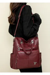 Detail shot of burgundy PU leather soft backpack with multiple zipper pockets and shoulder straps.