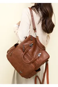 Detail view of the brown PU leather convertible backpack, showcasing back wear and zipper compartments.