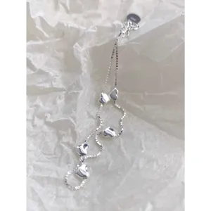 Primer plano detallado del pulsera de corazón de plata, con dijes de corazón lisos.