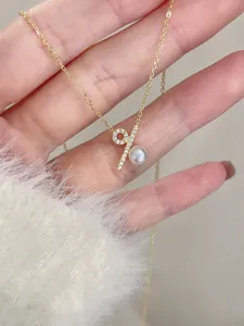 Primer plano detallado del collar colgante con símbolo de porcentaje, circonitas y perla.