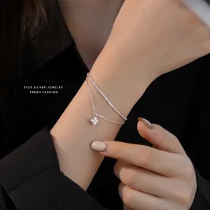 Close-up detail of double layer s925 silver bracelet with sparkling square zircon pendant.