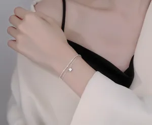 Exquisite double-layer silver bracelet detail featuring a sparkling square crystal pendant.