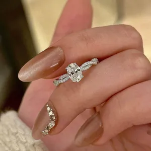 Primer plano del brillante anillo ovalado con banda trenzada pavé en mano elegante.