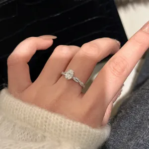 Primer plano de un brillante anillo de talla ovalada con una delicada banda pavé retorcida.