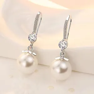 Primer plano detallado de los pendientes de plata con perla y circonitas brillantes.