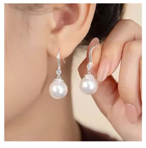 Primer plano detallado de elegantes pendientes de perlas blancas con gancho de plata.