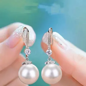 Primer plano detallado de elegantes pendientes de perlas con circonita brillante y plata.